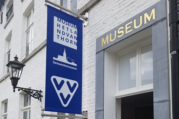 Banner van de VVV Thorn die hangt aan de façade van het museum