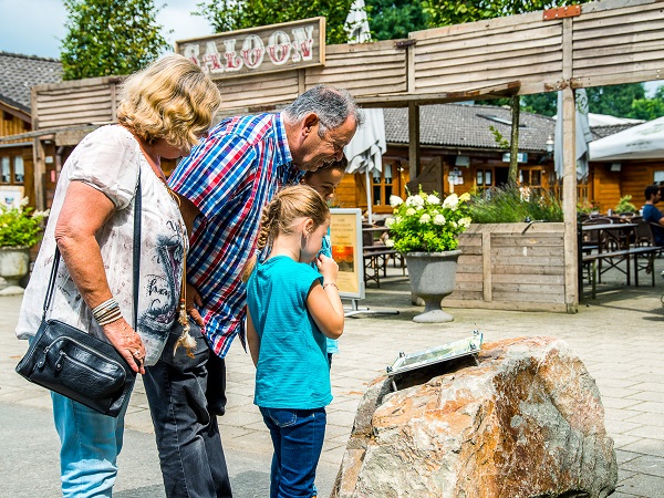 Couple is reading the information sign with their grandchildren