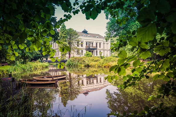 Castle de Berckt seen through a canopy with the pond in the foreground