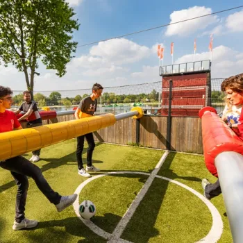 Groepsactiviteit bij Fun Beach Event & Leisurepark: jongeren spelen een potje levend tafelvoetbal op het buitenterrein.