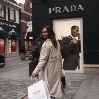 Vrouw kijkt om naar de camera terwijl ze aan het lopen is met winkeltassen