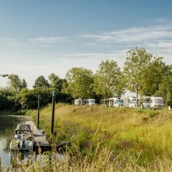 Campers staan op Camperplaats De Maasterp langs de Maas, met aanlegsteiger en uitzicht over het water.